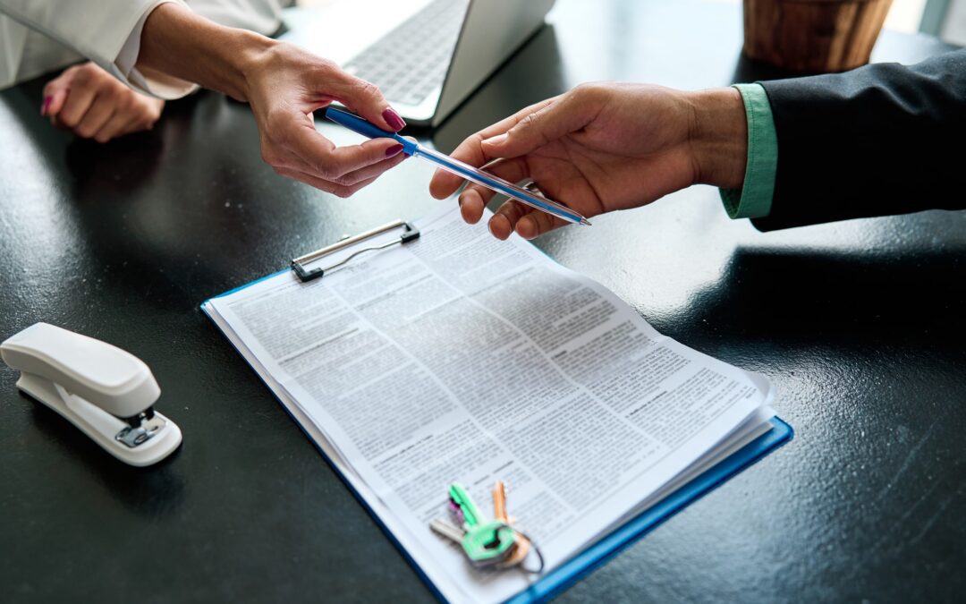 Close up view of an unrecognizable landlord agent giving a pen to sign papers to a client